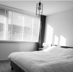 Slaapkamer met mooie witte houten jaloezieen.